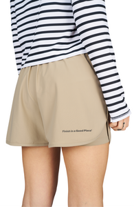 Women's running shorts in Warm Sand, featuring an inner lining and side vents. The 3-inch Flow Shorts offer a soft stretch and are made from ECONYL®. Podium Logo on the front and a reflective "Finish in a Good Place" slogan on the back. Includes one pocket in the inner lining and a hidden pocket at the back. Also available in a 5-inch length.