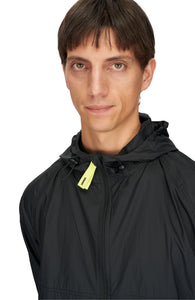 Men's ultra-lightweight running jacket (55g/m²) in Black. It features an adjustable hood, two side pockets, a back pocket, and side vents for enhanced ventilation. It is equipped with adjustable straps at the hem for a customizable fit. Made from 100% recycled nylon, it offers protection against wind and light rain. Additionally, it is packable, PFC-free, and features a reflective UNNA logo on the back, along with a UNNA patch on the zipper