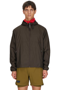 Men's ultra-lightweight running jacket (55g/m²) in Wren Brown. It features an adjustable hood, two side pockets, a back pocket, and side vents for enhanced ventilation. It is equipped with adjustable straps at the hem for a customizable fit. Made from 100% recycled nylon, it offers protection against wind and light rain. Additionally, it is packable, PFC-free, and features a reflective UNNA logo on the back, along with a UNNA patch on the zipper