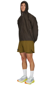 Men's ultra-lightweight running jacket (55g/m²) in Wren Brown. It features an adjustable hood, two side pockets, a back pocket, and side vents for enhanced ventilation. It is equipped with adjustable straps at the hem for a customizable fit. Made from 100% recycled nylon, it offers protection against wind and light rain. Additionally, it is packable, PFC-free, and features a reflective UNNA logo on the back, along with a UNNA patch on the zipper